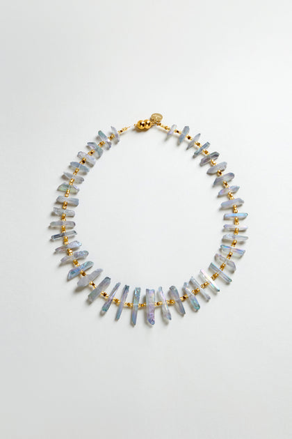 The Slate Quartz Necklace is a gold-plated statement piece with evenly spaced, irregularly shaped light purple quartz beads, shown on a plain white background.