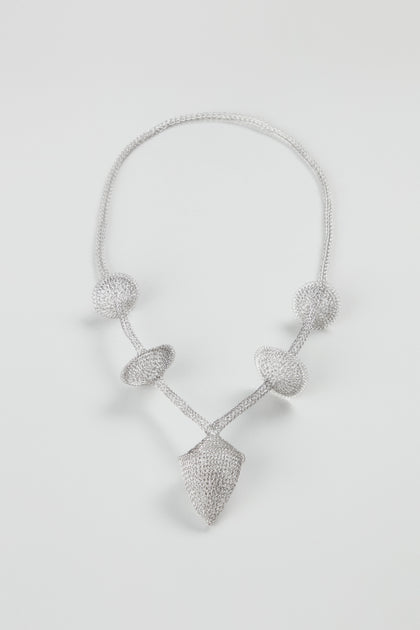 Hand Crocheted Snowdrop Necklace featuring textured geometric shapes—three spheres, a ring, and a shield-like pendant—crafted in stainless steel, displayed on a plain white background.