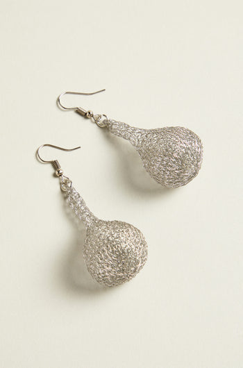 The hand crocheted craftsmanship is evident in these teardrop earrings, where intricate metallic threads form a delicate pattern on the light surface.