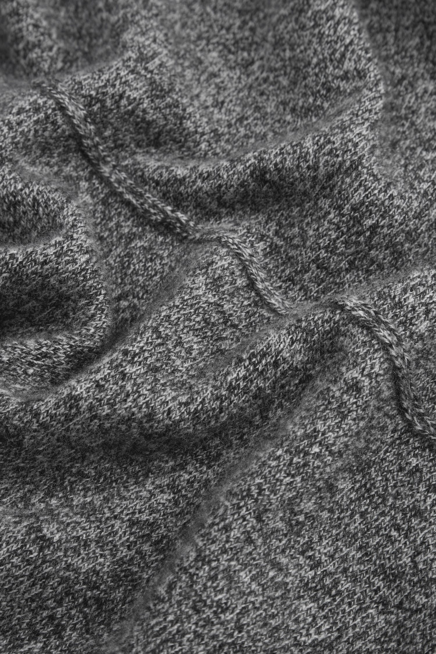 Close-up of gray textured wool fabric with a visible knitting pattern and soft folds, evoking the inviting warmth of the Black & White Merino Wool Cowl Neck Jumper.