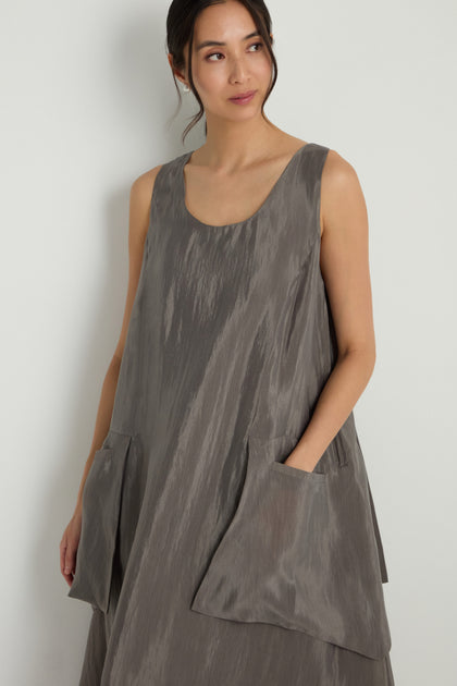 A woman models the Sleeveless Pocket Dress, featuring an A-line silhouette and large front pockets, standing against a light-colored backdrop.