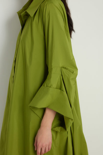 A person wearing the Taffeta Button-Through Lime Dress, a loose-fitting midi with flared cuffs, stands against a plain light background.