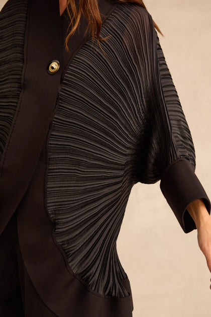 Black Pleated Jacket with batwing sleeves and a single metallic button closure at the neck.