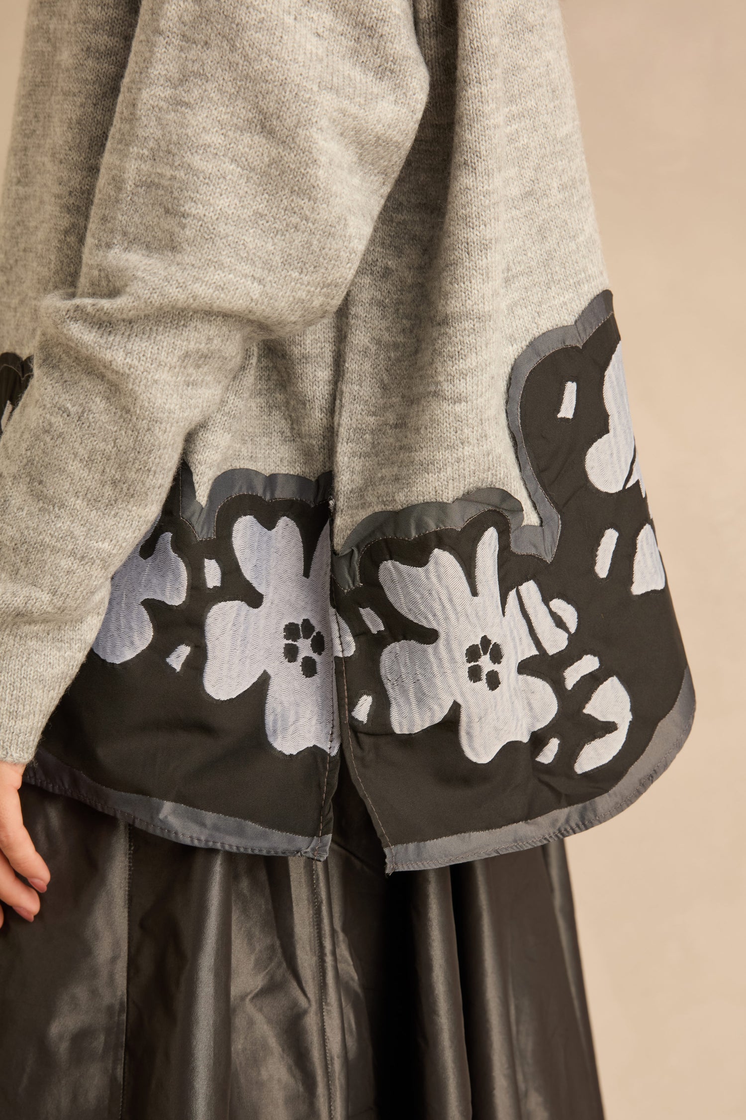 Flower Hem Knit sweater in grey, featuring a black hem panel with a grey floral appliqué.