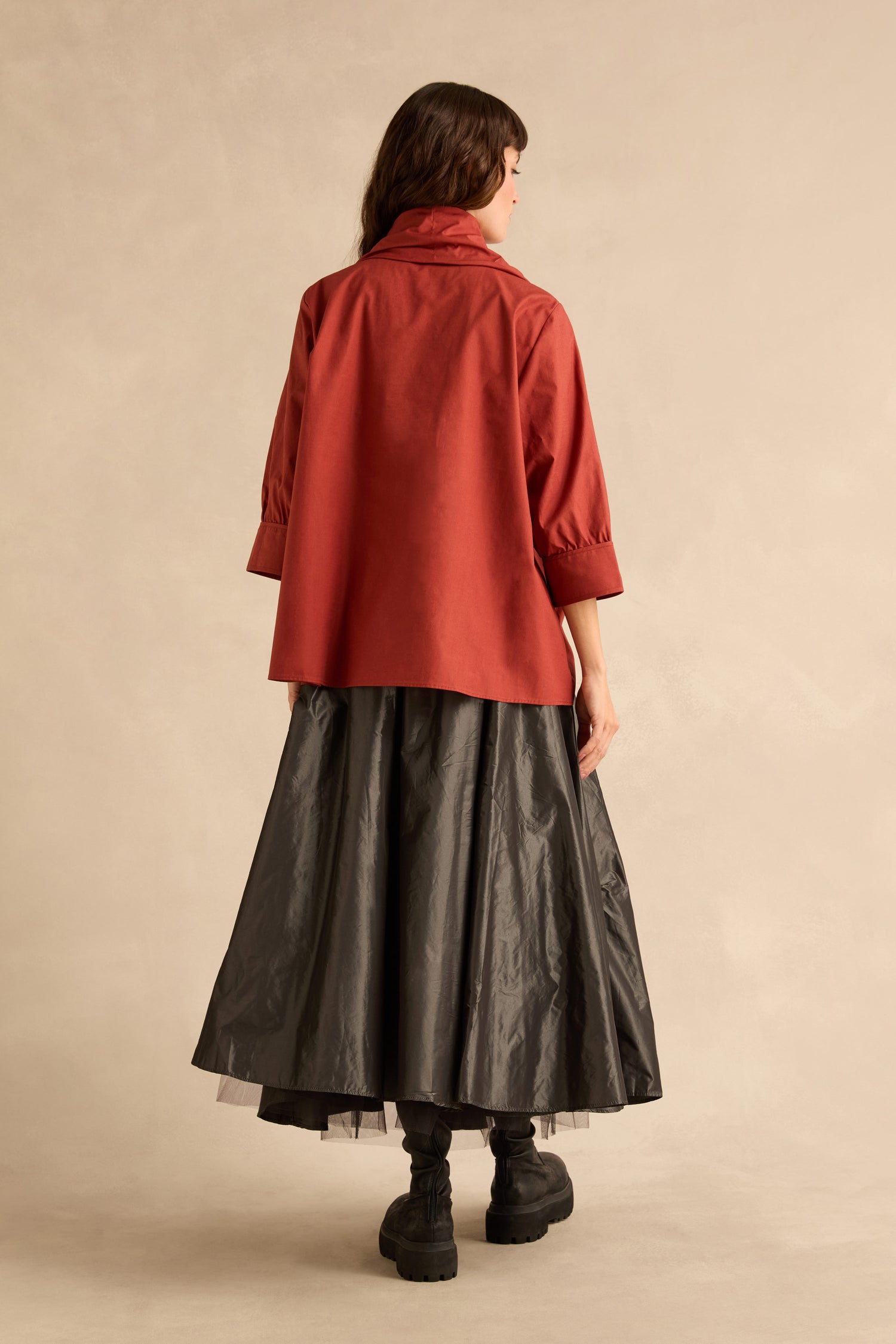 A person seen from behind wearing a Red Frill Neck Easy Top with a high frill neck and three-quarter sleeves, paired with a long, full black skirt and black platform boots.