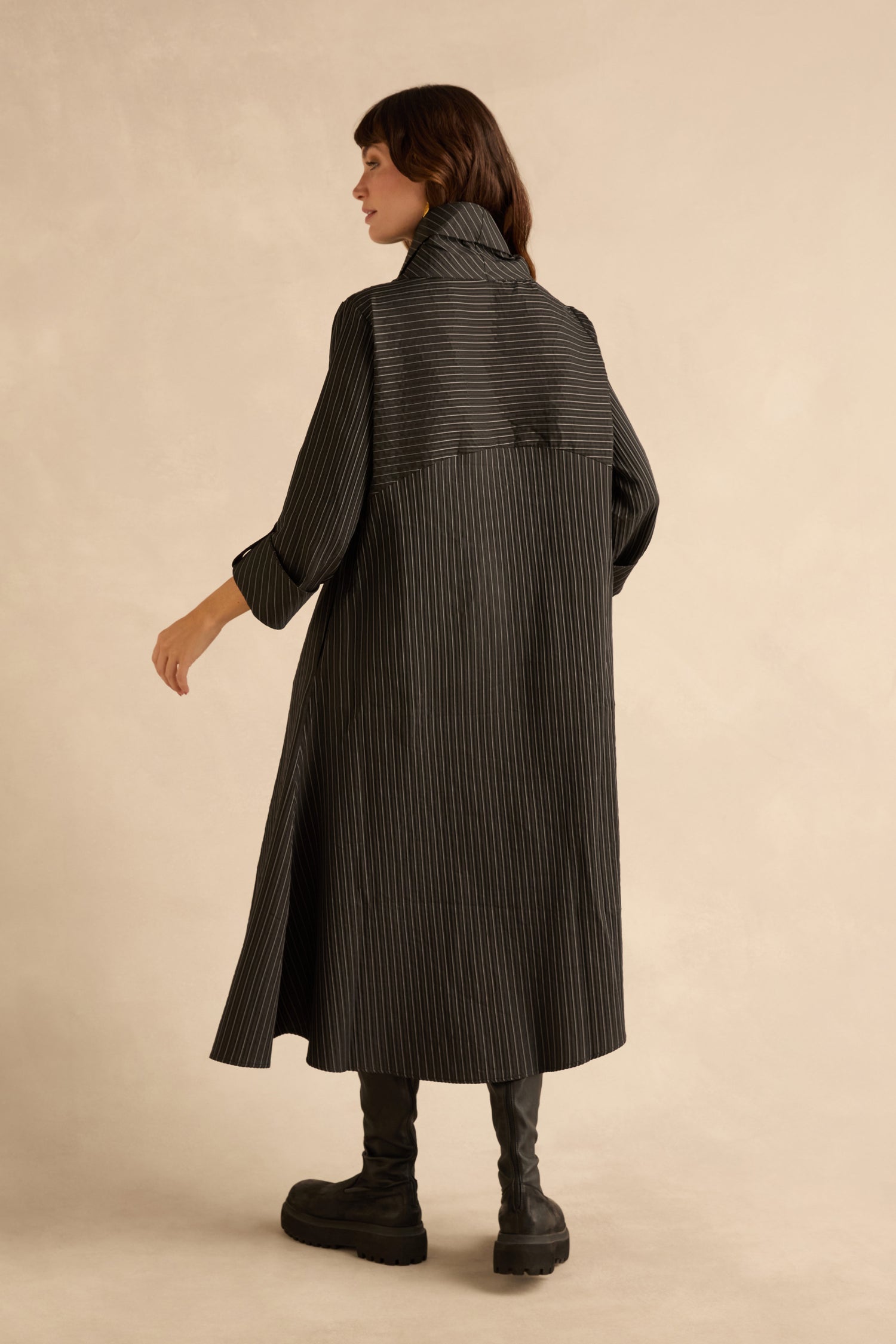 Seen from behind, a person wears a Pin Stripe Flower Detail Dress, a black pinstriped midi dress with a collar, bubble hem, and black platform boots.