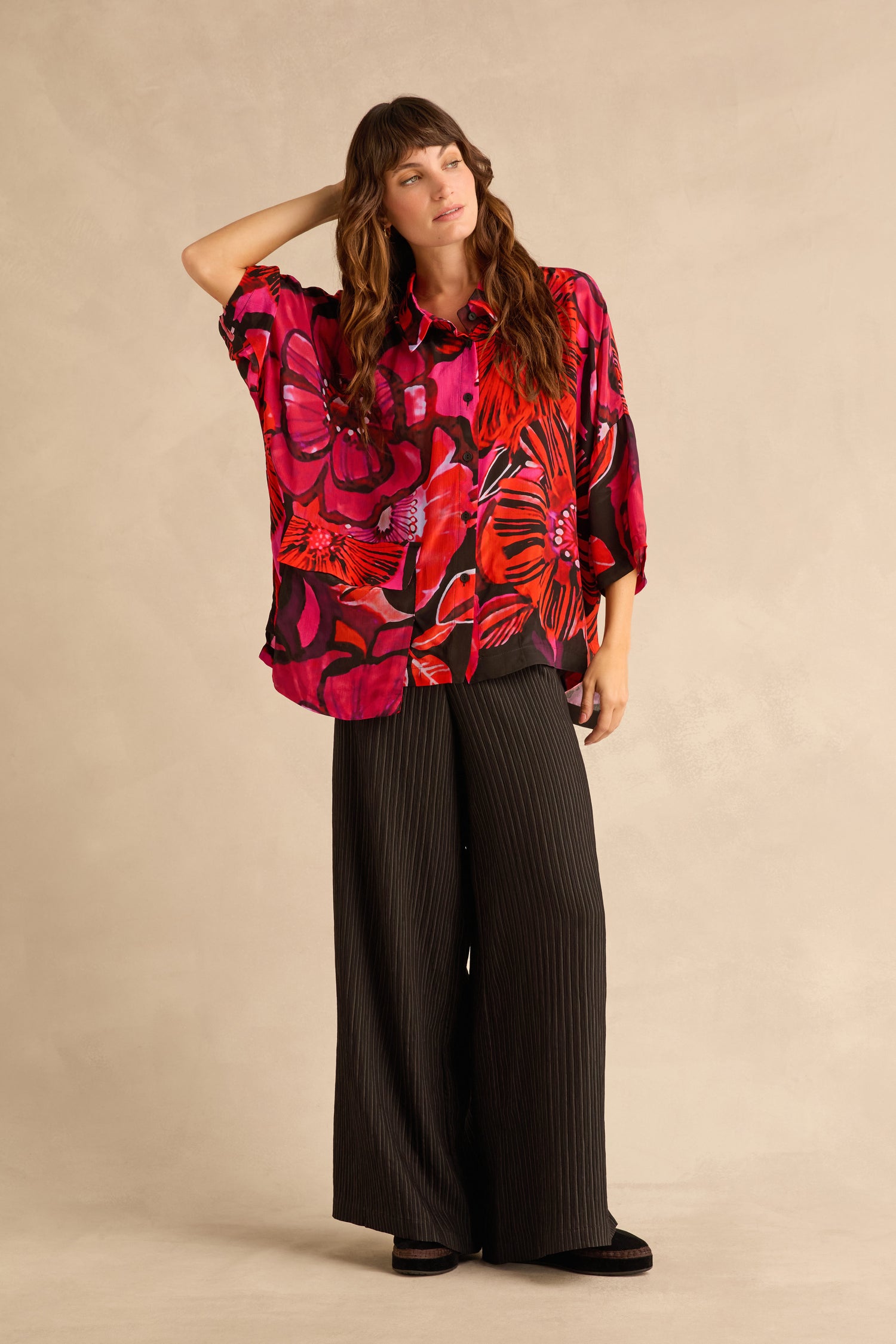A person wears a vibrant red and black Pocket Floral shirt paired with wide-leg black pinstripe trousers.