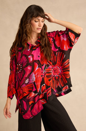 A woman wearing a Pocket Floral Shirt featuring a red, pink, and black pattern with a single chest pocket.