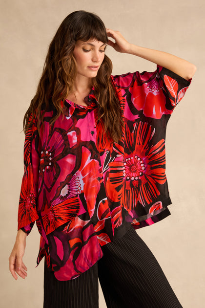 A woman wearing a Pocket Floral Shirt featuring a red, pink, and black pattern with a single chest pocket.