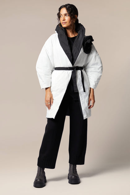A woman wearing a white Reversible Puffa with floral applique, paired with black pants.