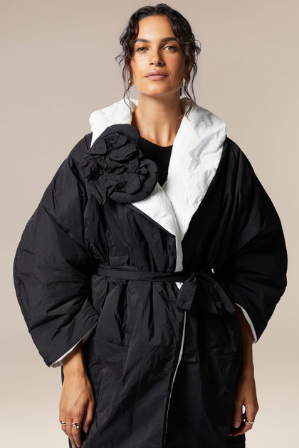A woman wearing a Reversible Puffa with a white collar and flower applique.