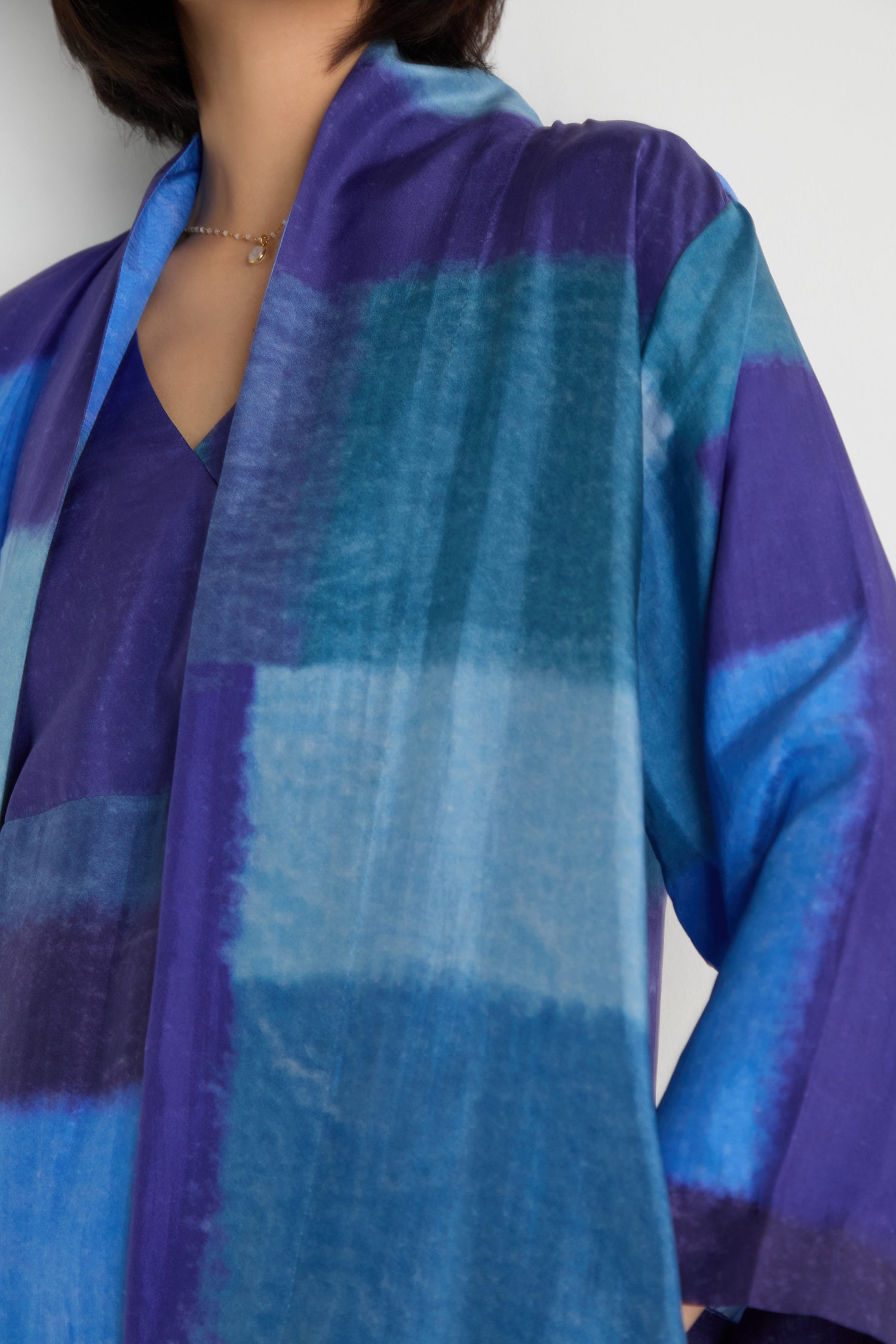 A person wears the Blurred Blocks Easy Jacket, featuring a blue and purple pattern, shown from the shoulders down against a plain background.