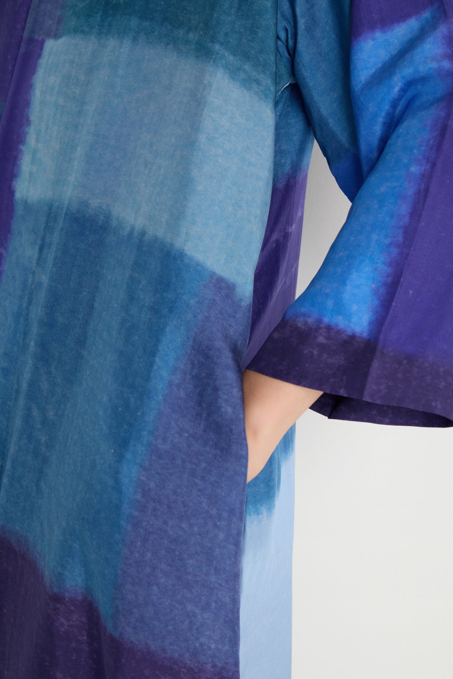 Close-up of a person wearing the Blurred Blocks Easy Jacket, featuring blue and purple gradient-patterned silk and long sleeves with a side pocket—a perfect lightweight layering piece.
