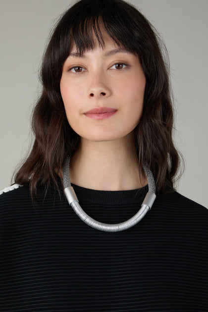 A woman wears the Flow Cord Necklace, highlighting the bold elegance of contemporary jewellery.