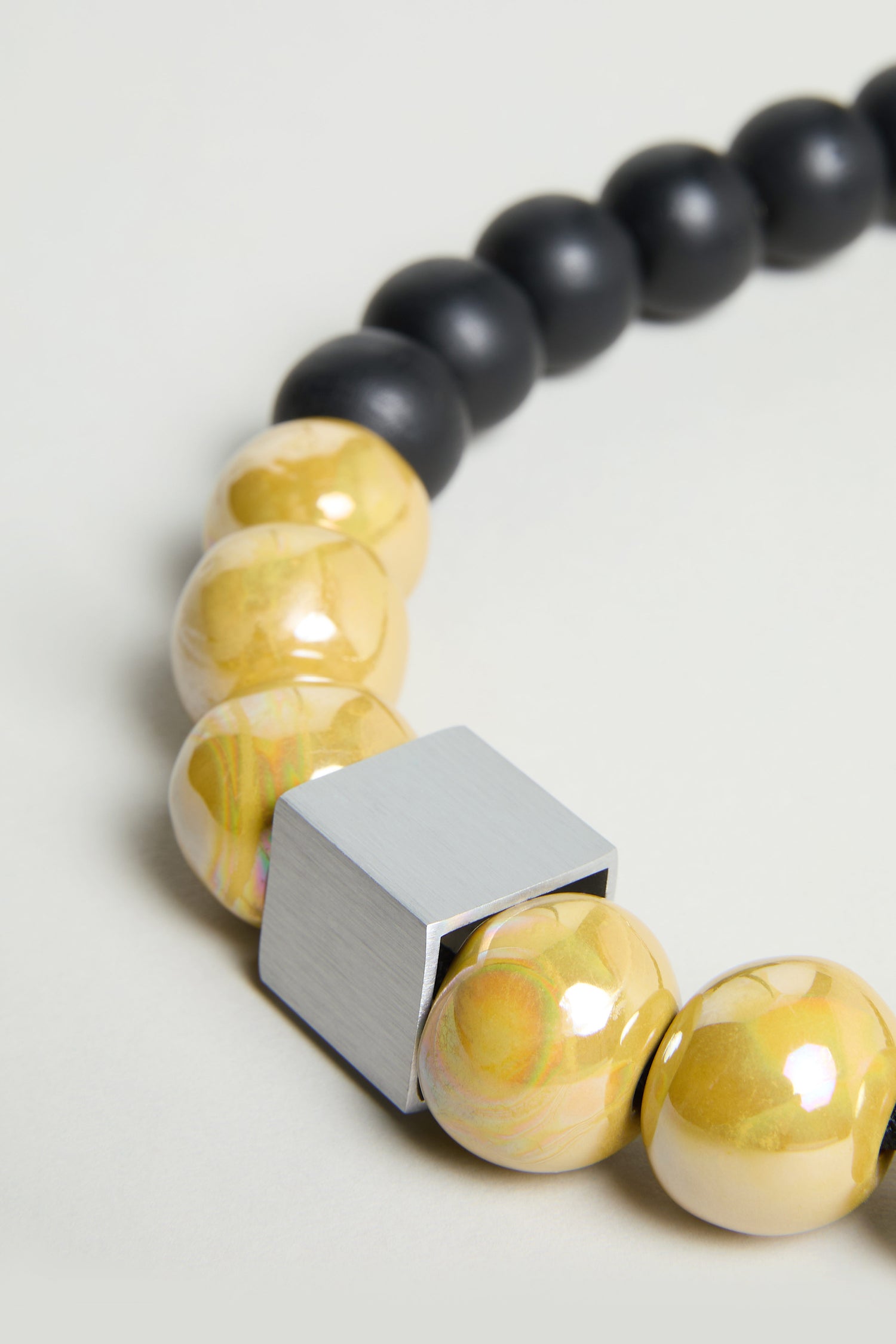 Close-up of the Elements Necklace by Christina Brampti: featuring shiny yellow beads, matte black beads, and a large square metallic bead for a bold, contemporary statement.