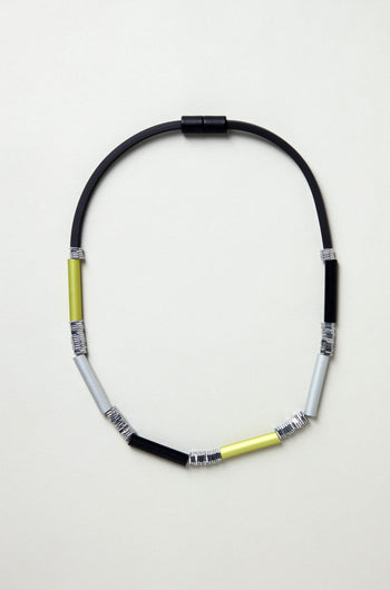 The Atomic Silver Aluminium Hematite Necklace features a sleek black cord with yellow, silver, and black metal coil-wrapped beads—ideal for minimalist jewelry lovers or fans of Christina Brampti-inspired style.