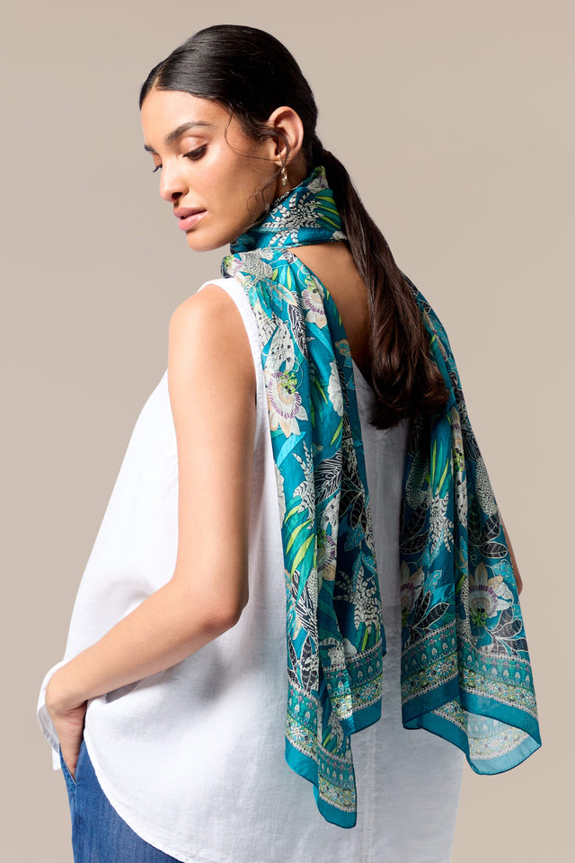 The back view of a woman wearing a Passion Flower Silk Scarf with a blue paisley motif.