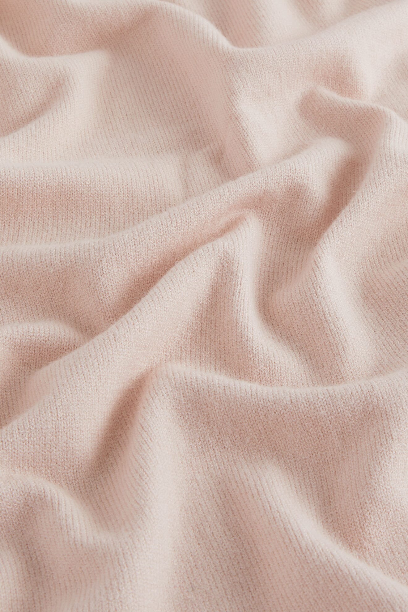 Soft folds of light pink, ribbed knit fabric highlight its gentle drape and texture—perfect for a luxury Knit Scarf or cozy winter accessory.