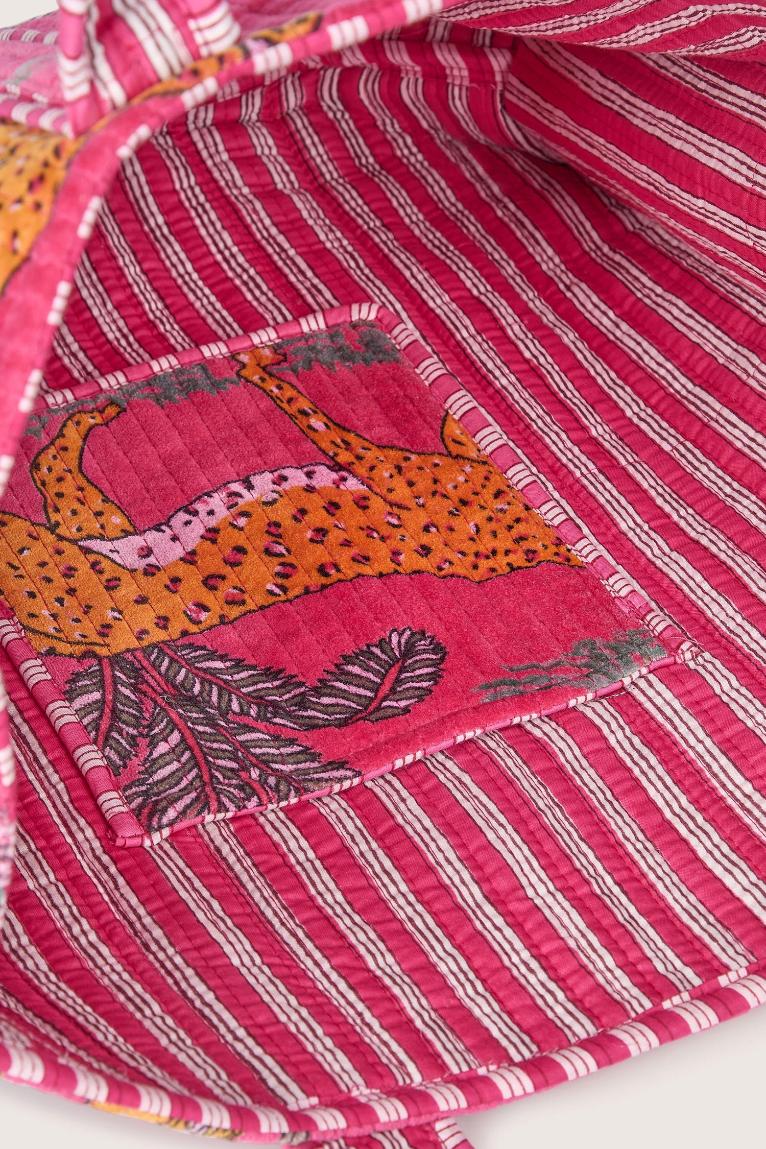 Close-up of the interior of a Jungle Print Velvet Bag featuring a pink striped fabric with an embroidered cheetah and foliage design on a small inner pocket.