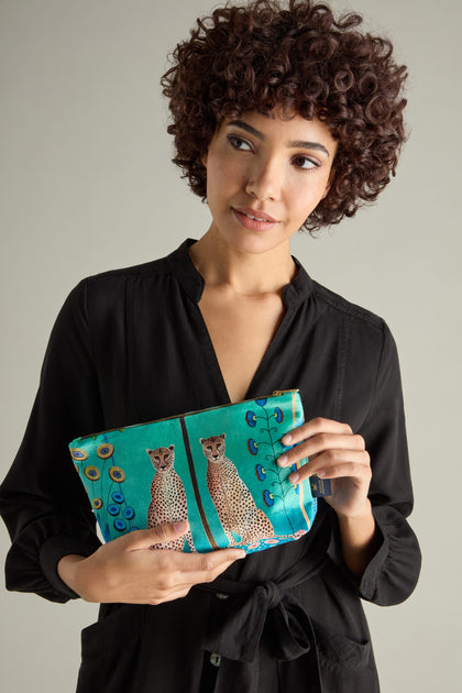 A person in a black dress holds the Large Sunshine Through My Window Velvet Bag adorned with a Cheetahs design, adding a touch of wild elegance.