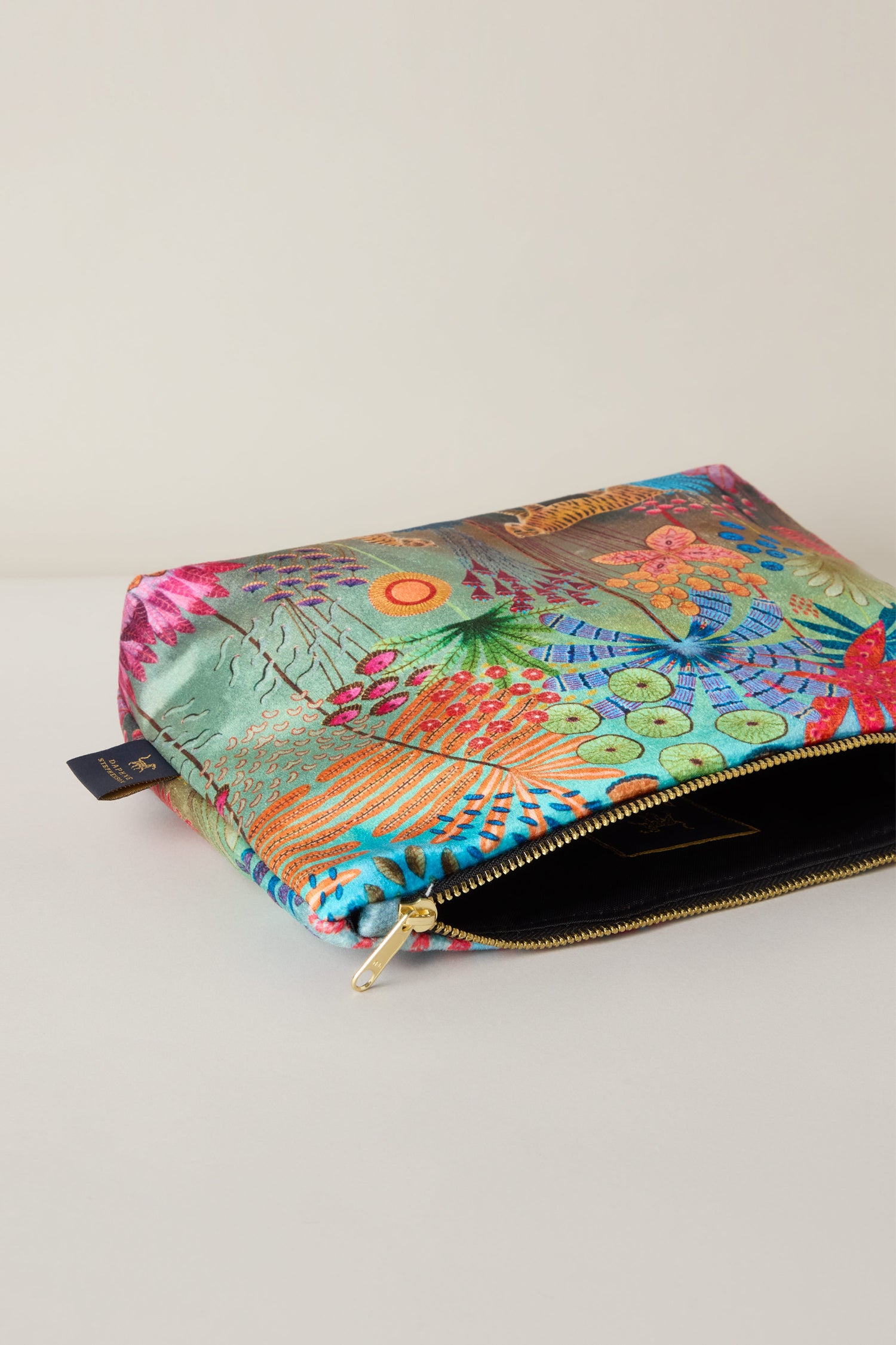 A Large Tale of Two Tigers Velvet Bag, featuring a colorful floral pattern and zipper reminiscent of Daphne Stephenson's vibrant art style, laid flat on a light surface.