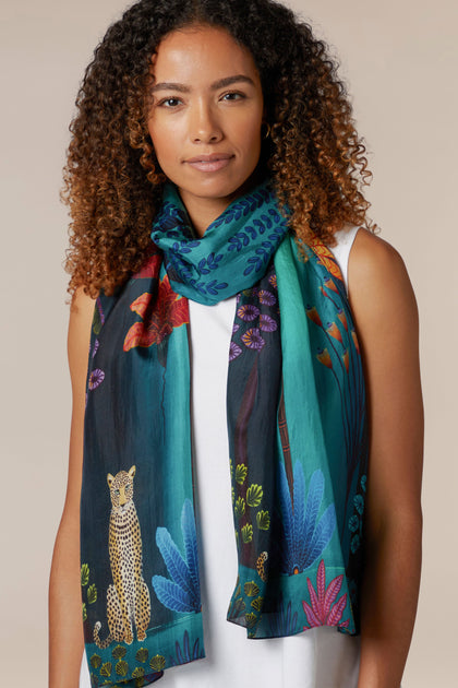 A woman wearing the Twilight Jungle Silk Scarf with a cheetah on it.