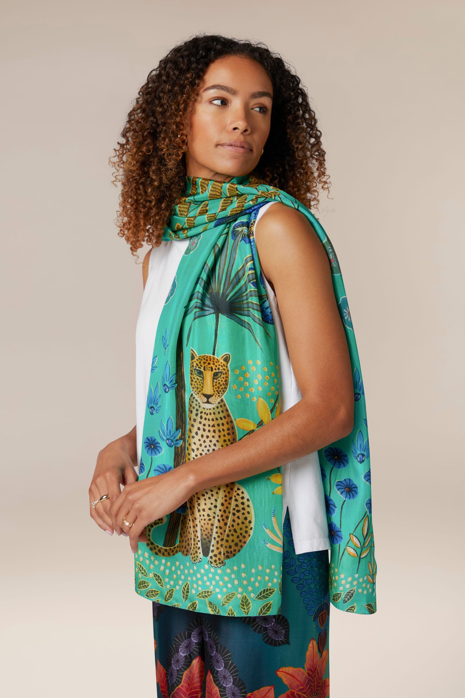 A woman wearing a Leopard in Moonlight Silk Scarf with a cheetah print.