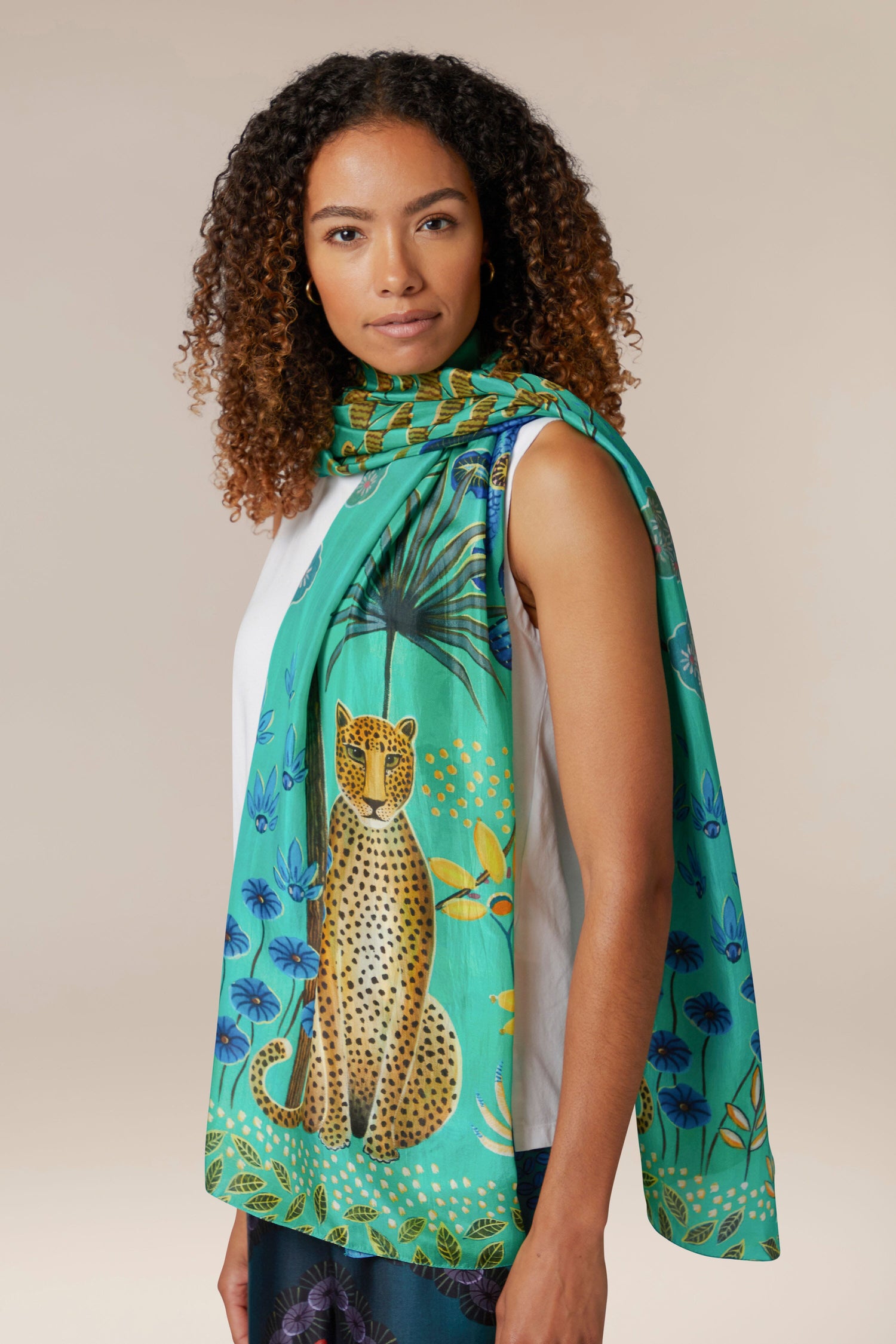 A woman wearing a Leopard in Moonlight silk scarf, made from ethically sourced materials.