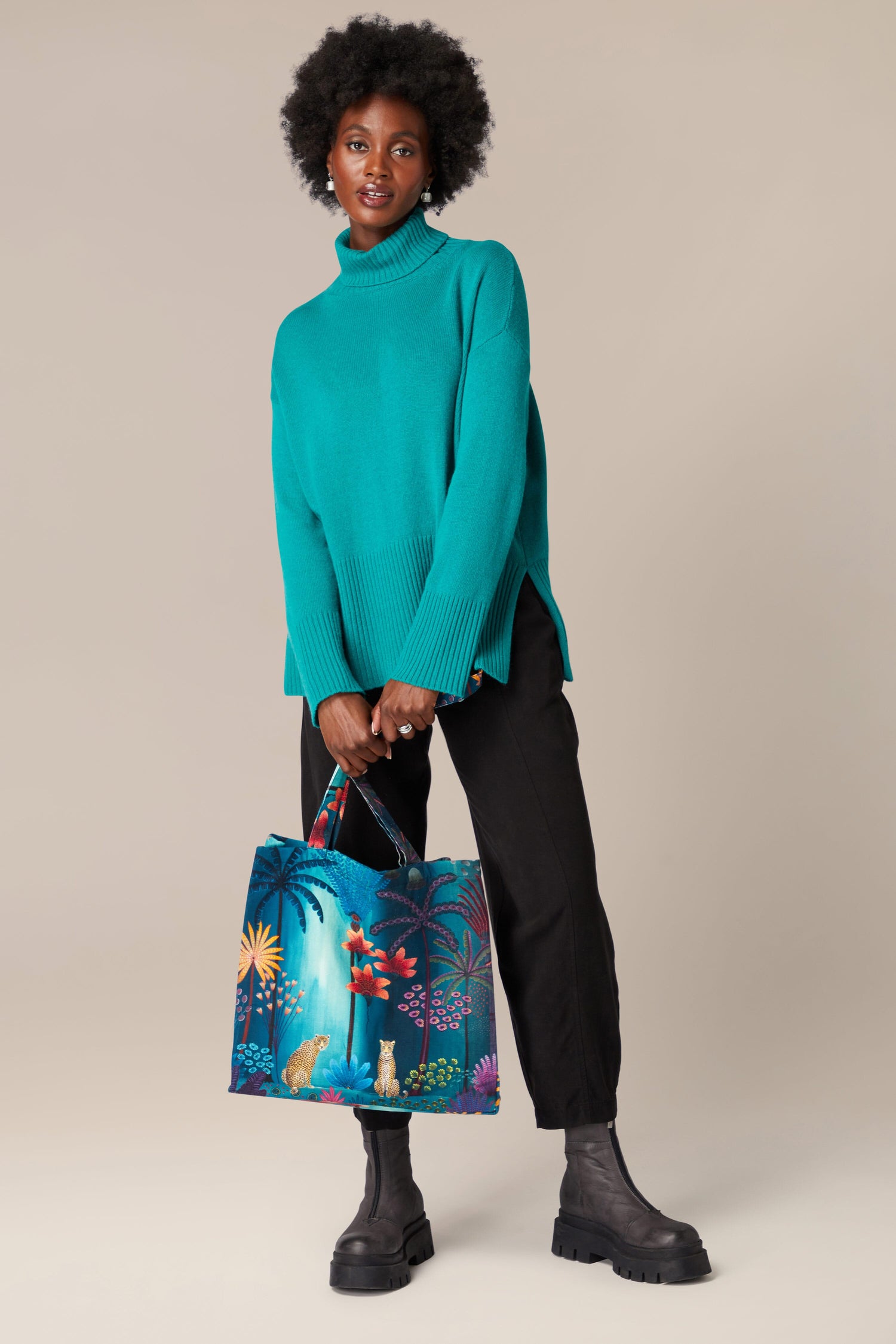 A woman holding a Twilight Jungle Tote Bag with a tropical print of jungle scenes.