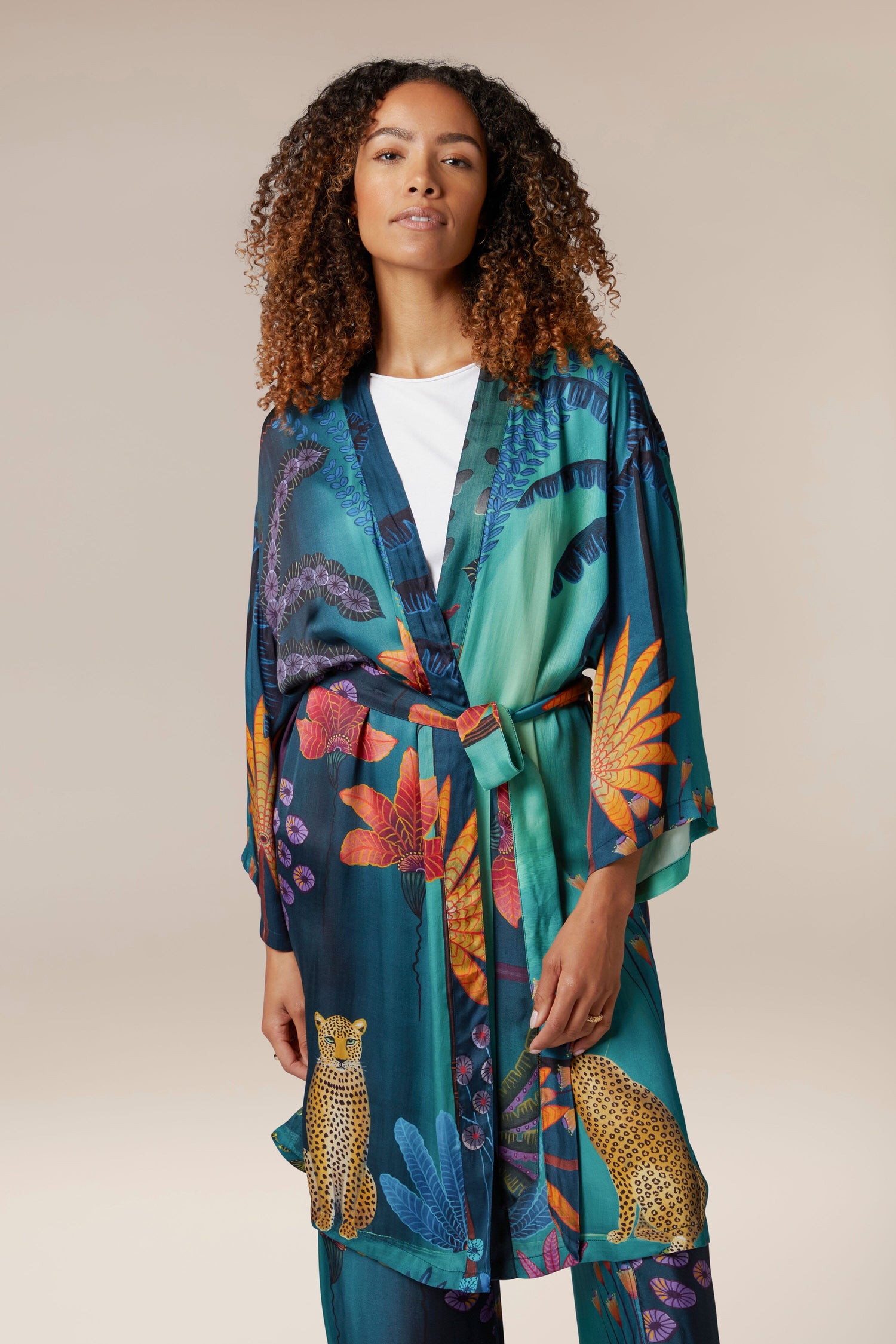 A woman wearing a Twilight Jungle Gown, a longline silhouette tropical print robe made from lustrous modal fabric.