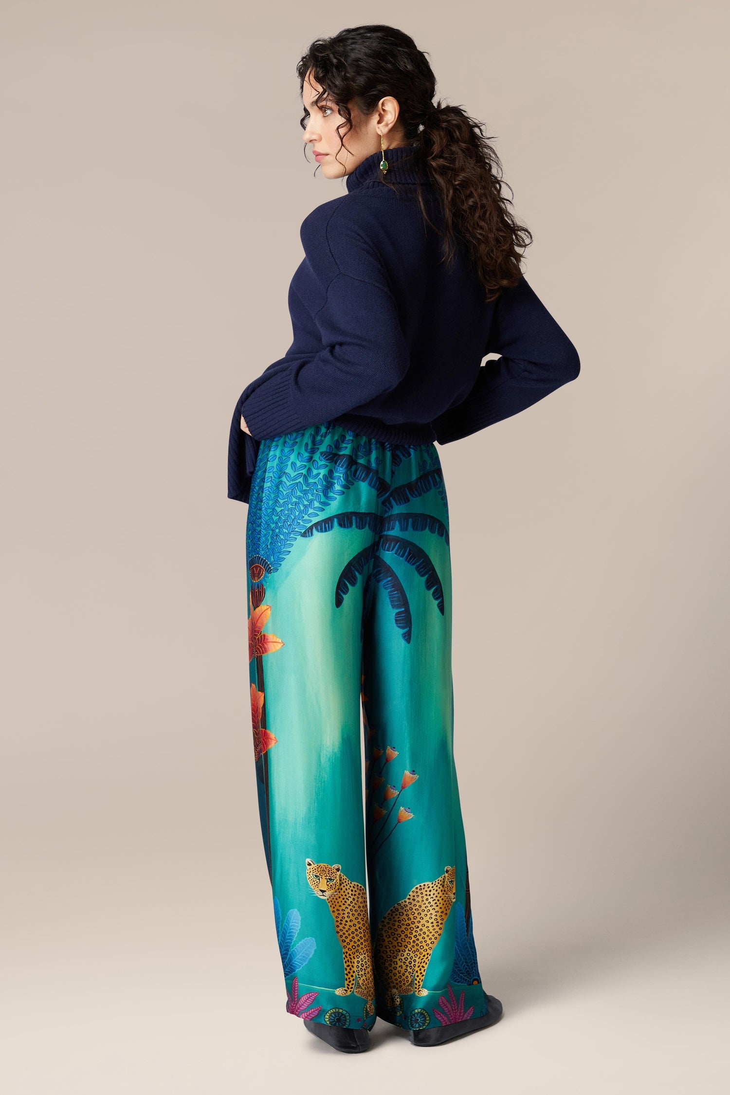 The back view of a woman wearing Twilight Jungle Trousers with an exotic tropical scene print.