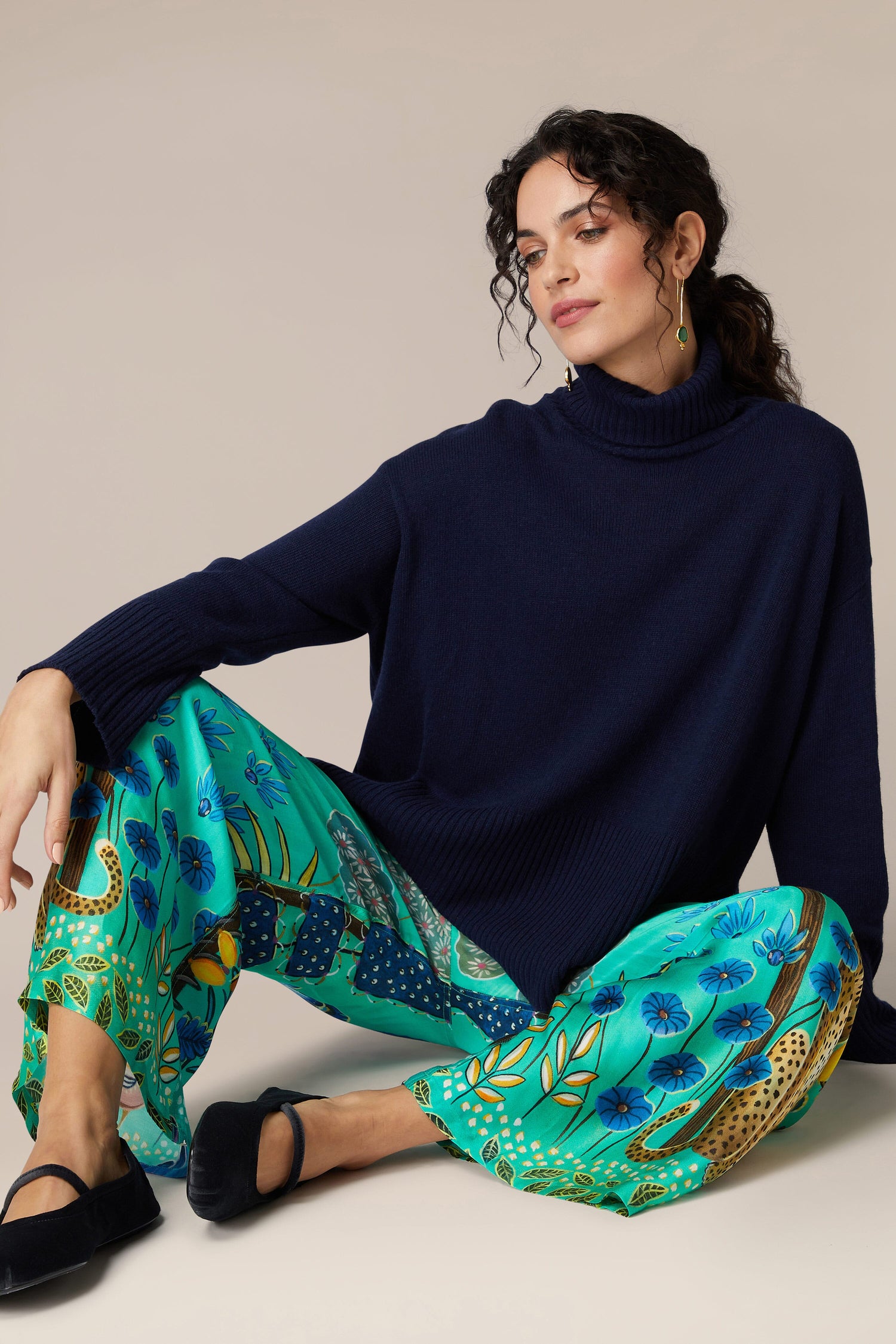 A woman wearing a blue turtleneck sweater and Leopard in Moonlight trousers.