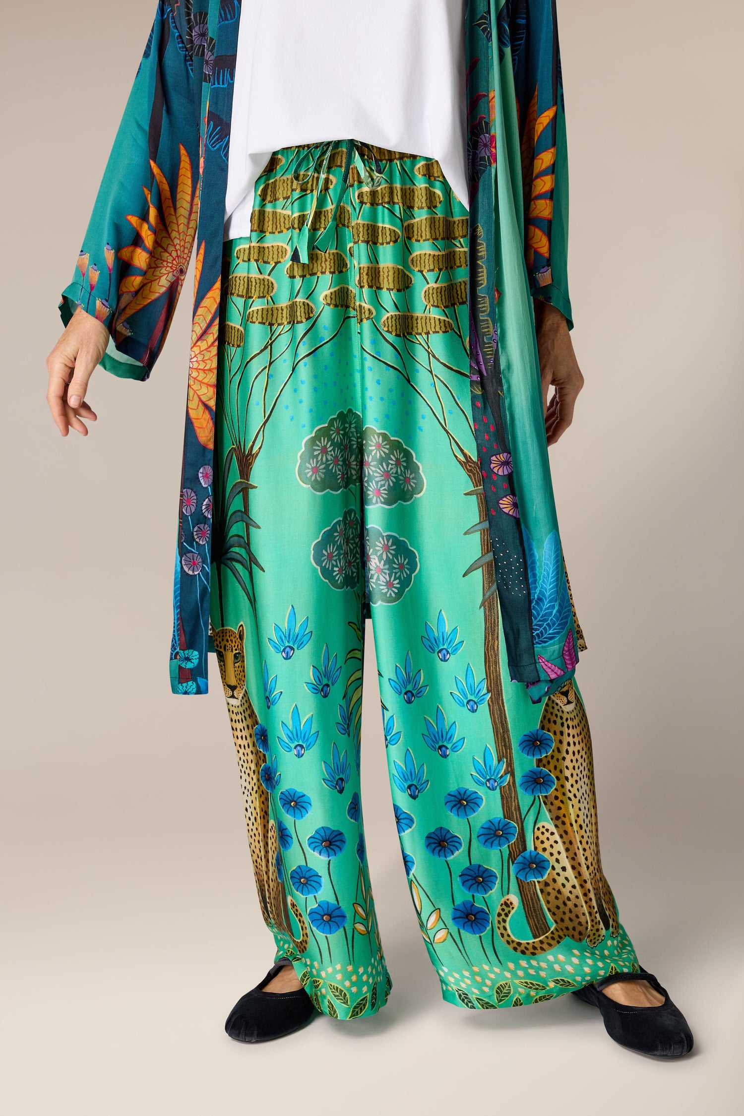 A woman wearing Leopard in Moonlight trousers in a green and blue robe.