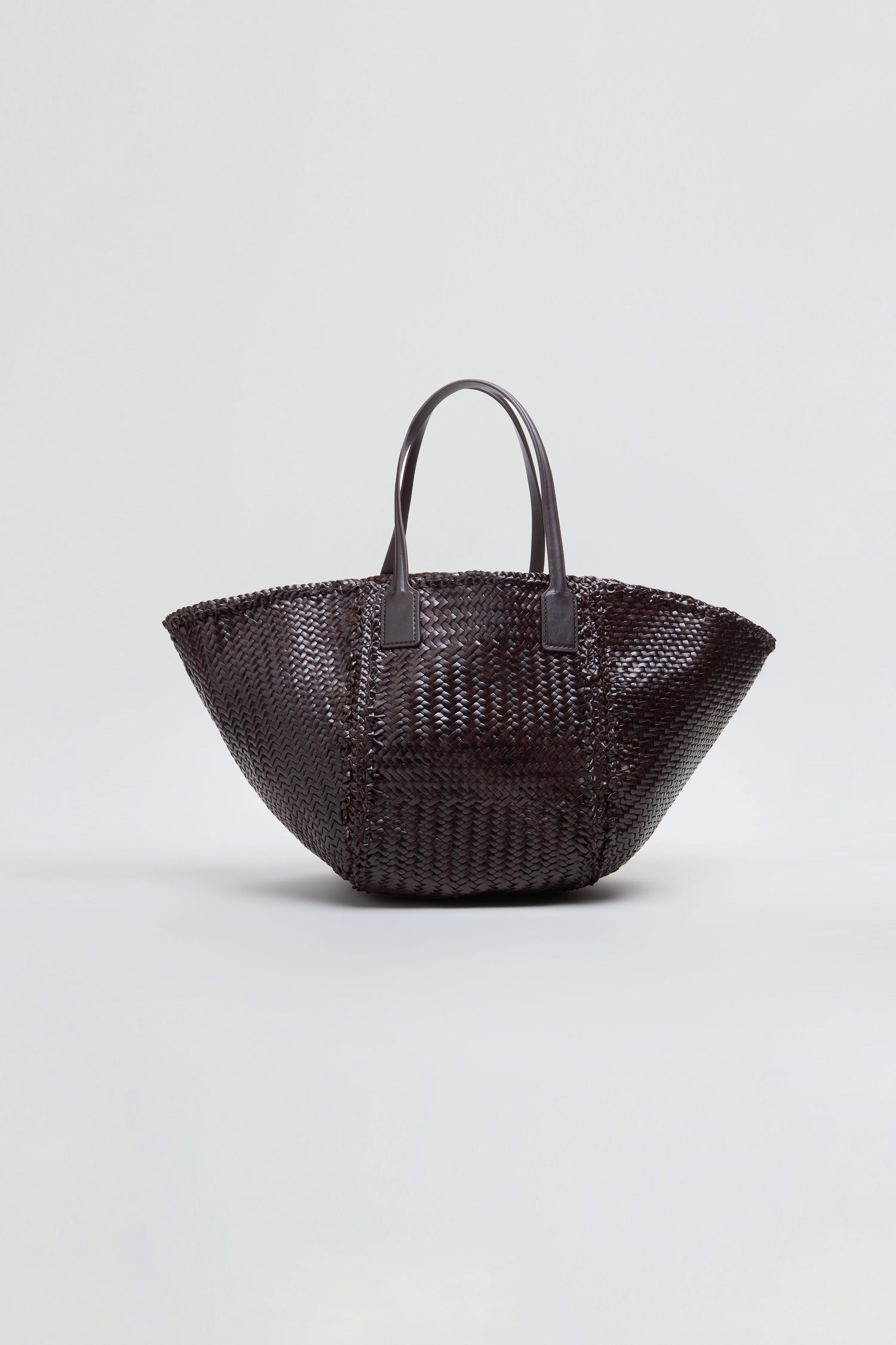 The Teresa Woven Leather Bag, featuring handwoven craftsmanship in dark brown leather with two handles, is displayed against a plain light gray background.
