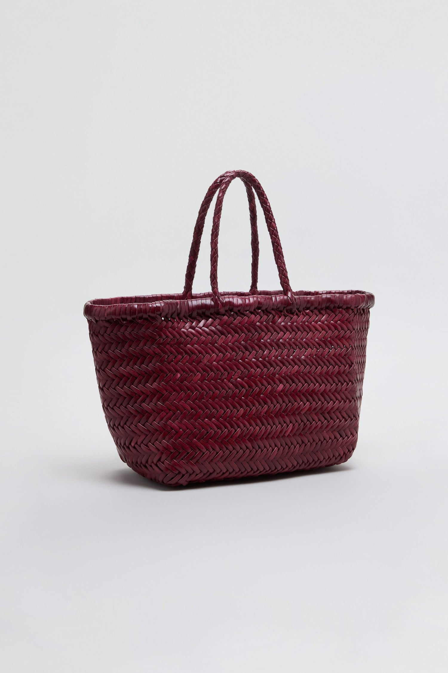 Displayed on a light gray background, the Small Triple Jump Woven Leather Bag features a maroon, basket-style handwoven leather design with two handles, showcasing Dragon Diffusion’s signature craftsmanship.