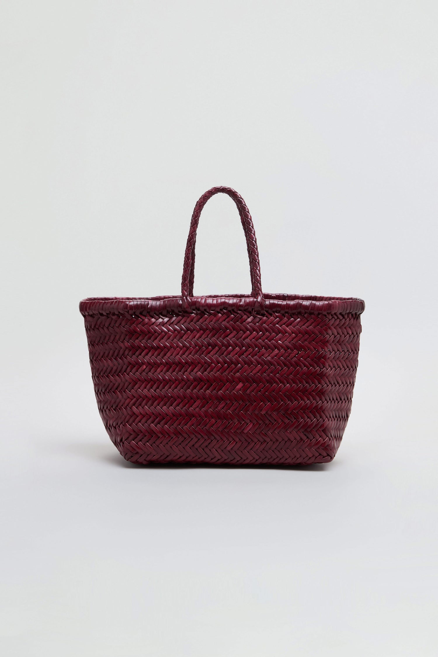 A dark red Small Triple Jump Woven Leather Bag with two handles sits against a plain light background. This beautiful piece from Dragon Diffusion highlights exquisite craftsmanship in every handwoven detail.
