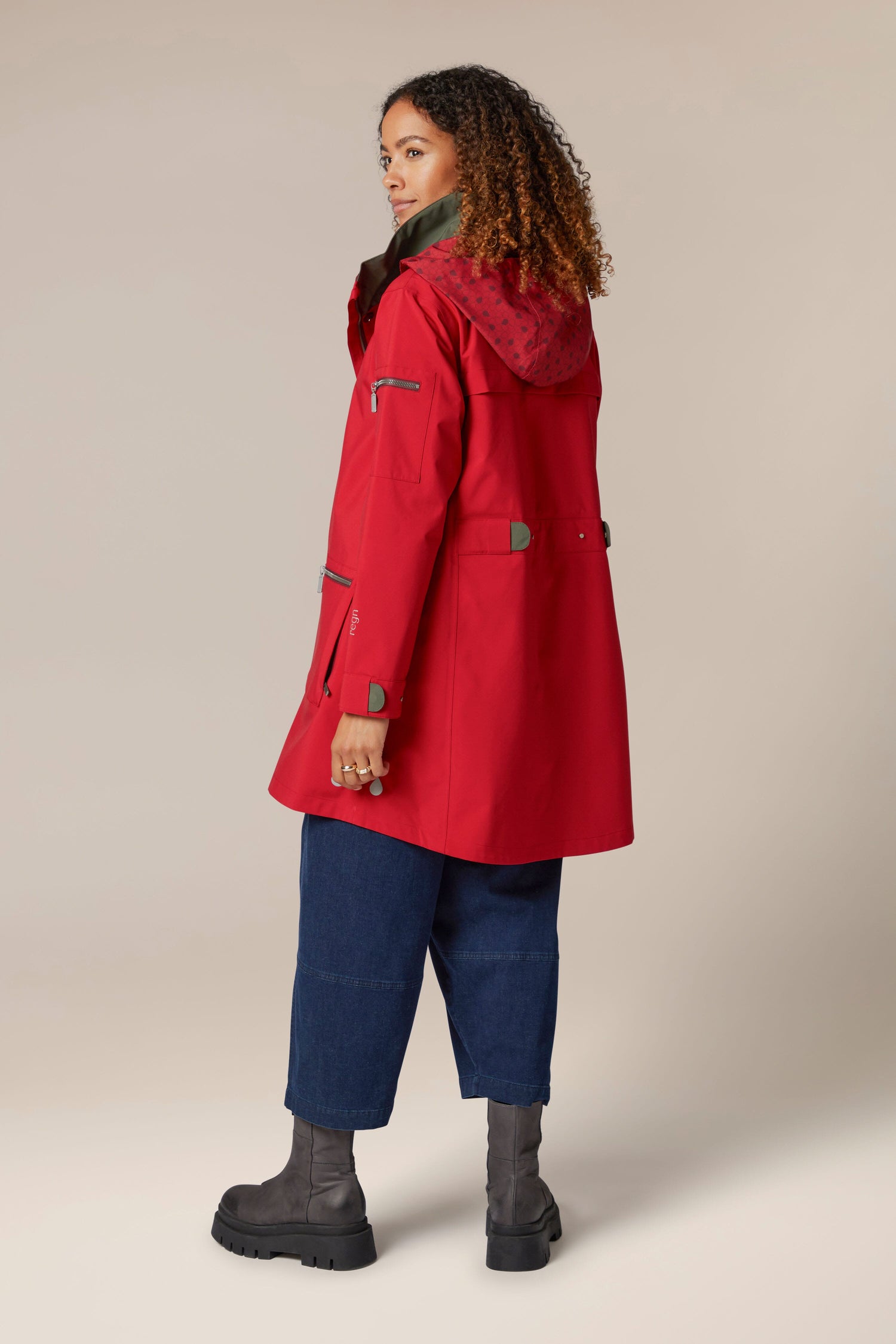 The back view of a woman wearing a 5 Pocket Hooded Rain Jacket with adjustable wrists.