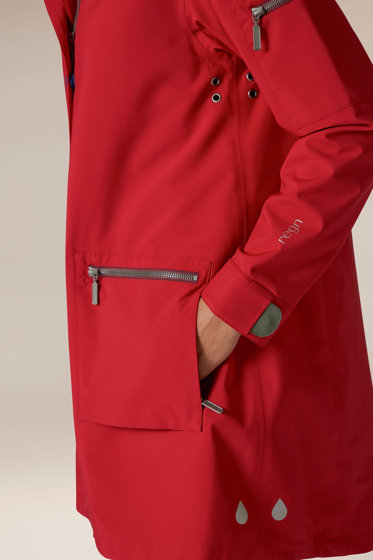 A woman wearing a 5 Pocket Hooded Rain Jacket in Regn, with adjustable wrists.