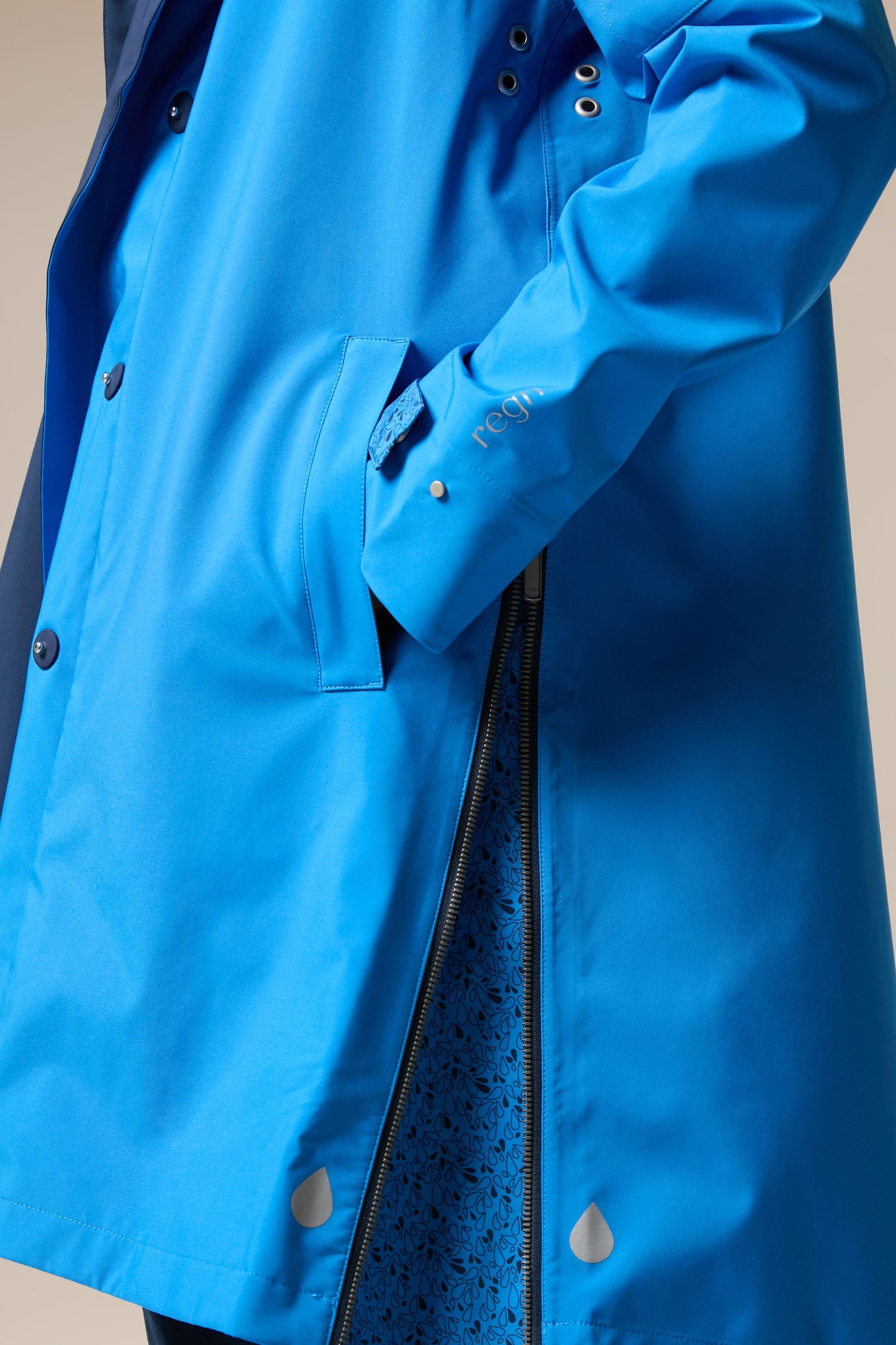 A woman wearing the Denise Wide Collar Rain Jacket in a bright blue color from Scandi brand Regn.