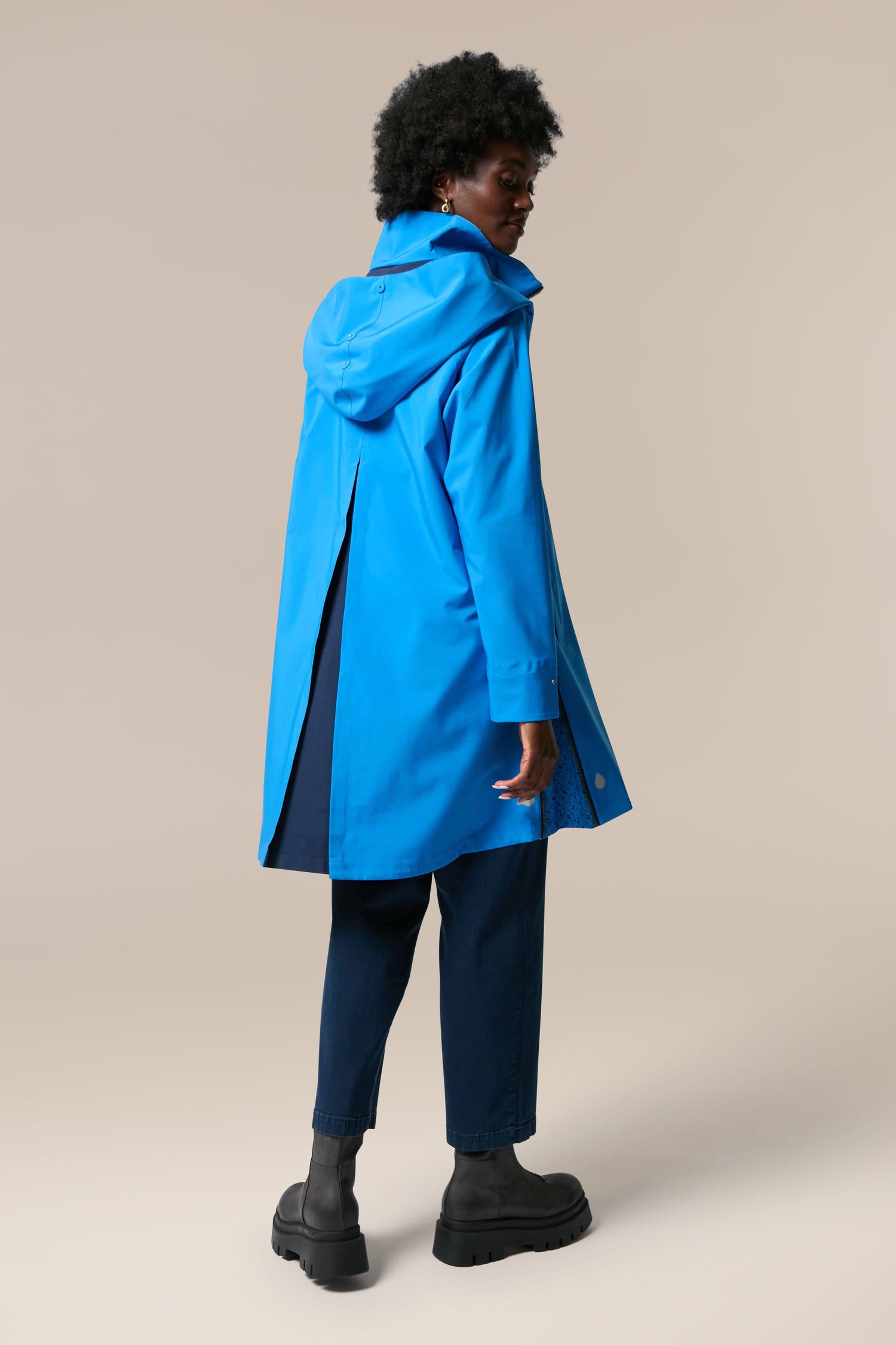 The back view of a woman wearing the Denise Wide Collar Rain Jacket in a blue raincoat.