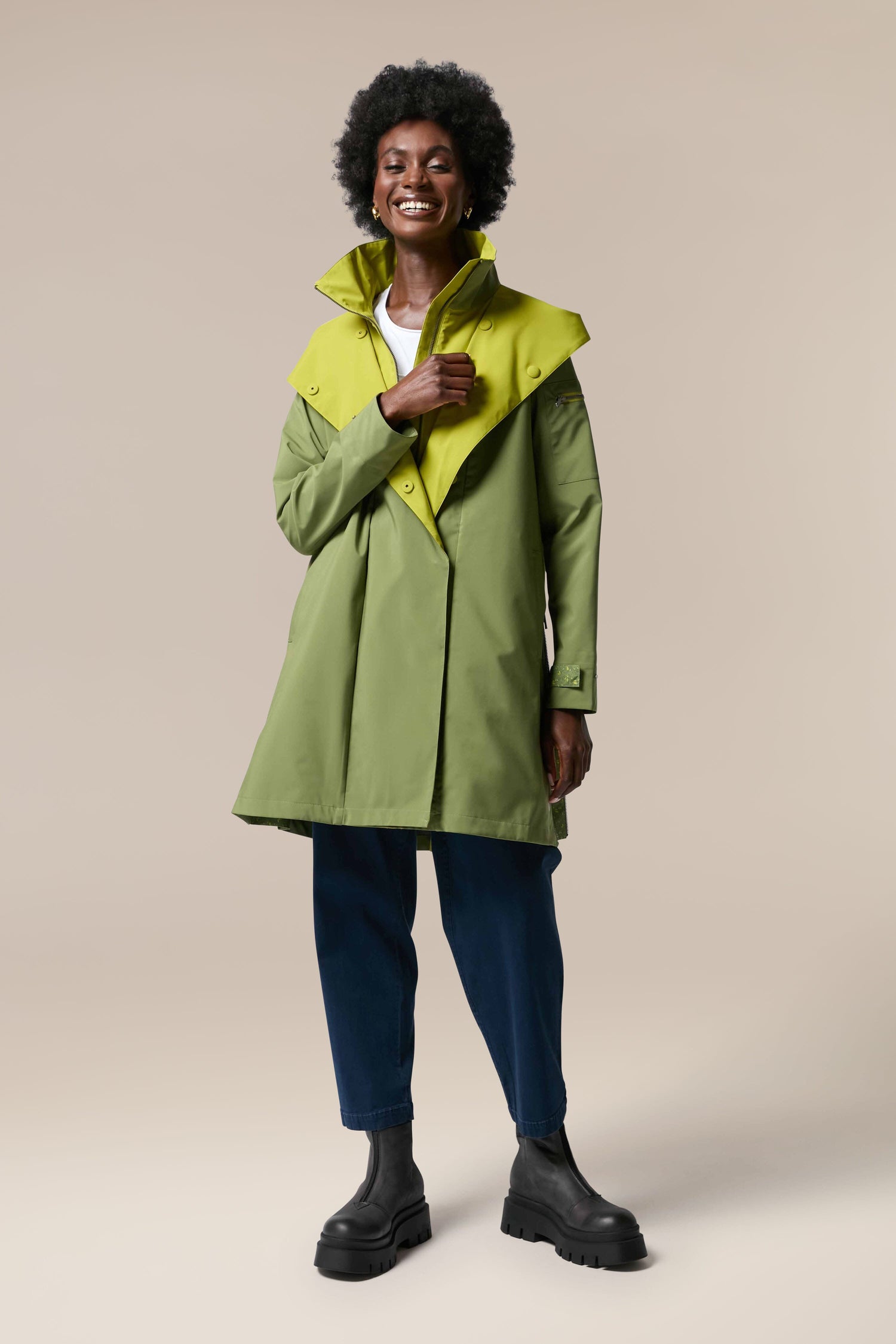 A woman wearing the Denise Wide Collar Rain Jacket from Scandi brand Regn, made with storm-proof, sustainability-accredited technical fabrics.