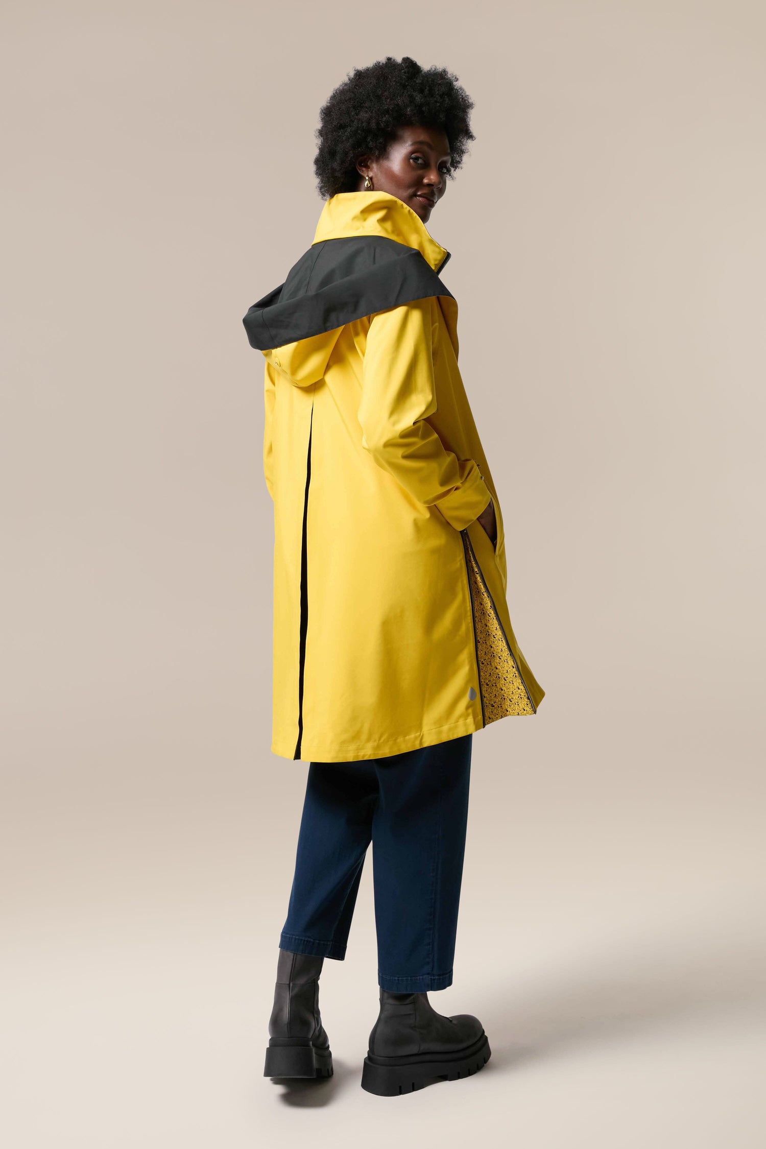 A woman wearing the Denise Wide Collar Rain Jacket from the sustainability-accredited Scandi brand Regn.