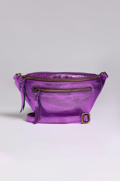 The Metallic Leather Crossbody Bag in iridescent purple features a front zipper pocket, two tassels, and an adjustable strap, shimmering beautifully against a plain background.