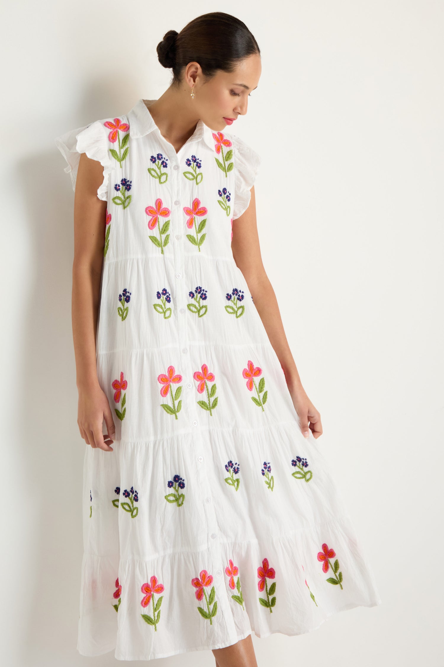 A woman wears the Embroidered Flower Frill Sleeve Dress, featuring colorful floral embroidery, standing against a plain light background.