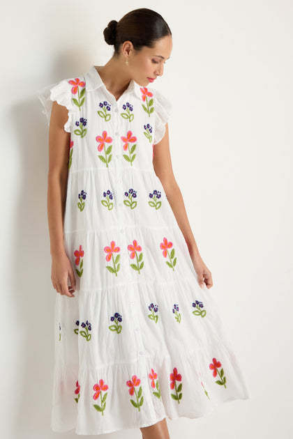 A woman wears the Embroidered Flower Frill Sleeve Dress, featuring colorful floral embroidery, standing against a plain light background.