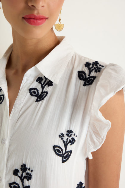Close-up of a woman wearing the Embroidered Navy Floral Frill Sleeve Dress, styled with gold earrings.