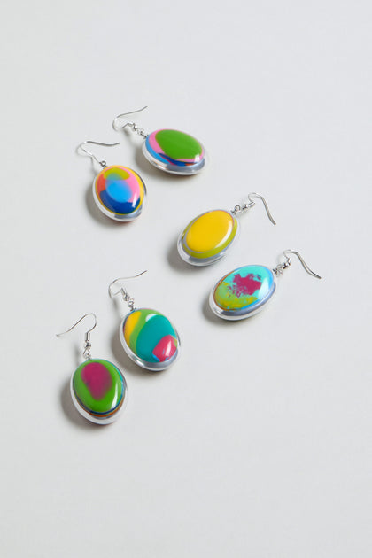 Five pairs of Rainbow Pebble Earrings with silver hooks, each displaying a colorful abstract swirl in green, yellow, pink, blue, and orange tones, are arranged on a white background.