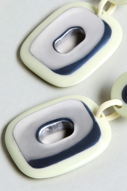 Close-up of two connected cream and gray rectangular links with oval openings and glossy finish—ideal as bold statement Deco Earrings.