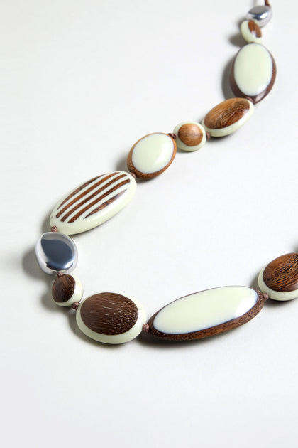 The Humbug Necklace showcases oval and round beads in cream, brown, and silver hues, made from natural wood and recycled aluminium.