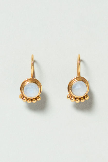 Moonstone Earrings: Gold drop earrings featuring round, translucent white moonstones in circular frames, each accented with three small gold beads at the base.